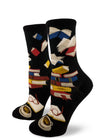Black crew socks for women with stacked multicolored books and airborne books above, with open book, glasses and cup and saucer below.