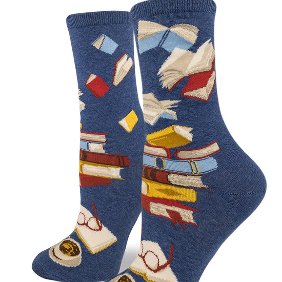 Blue crew socks for women with stacks of books and books flying through the air, with an open book, glasses and cup at the bottom.