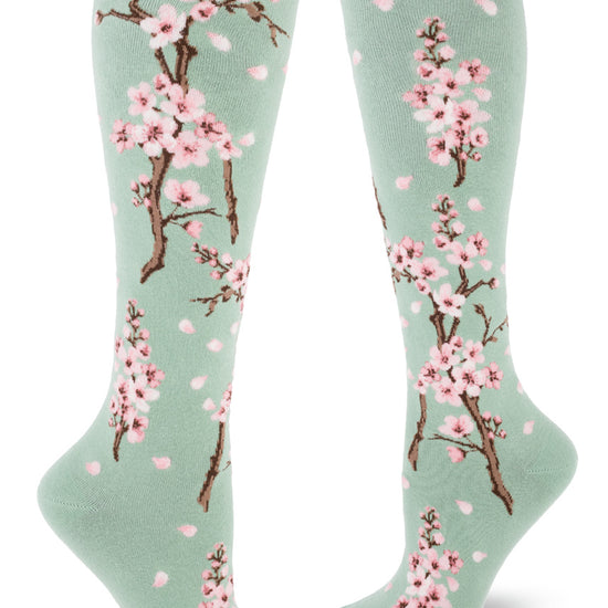 Pale green knee socks with branches of pink cherry blossoms and falling pink petals.