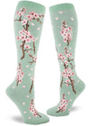 Pale green knee socks with branches of pink cherry blossoms and falling pink petals.