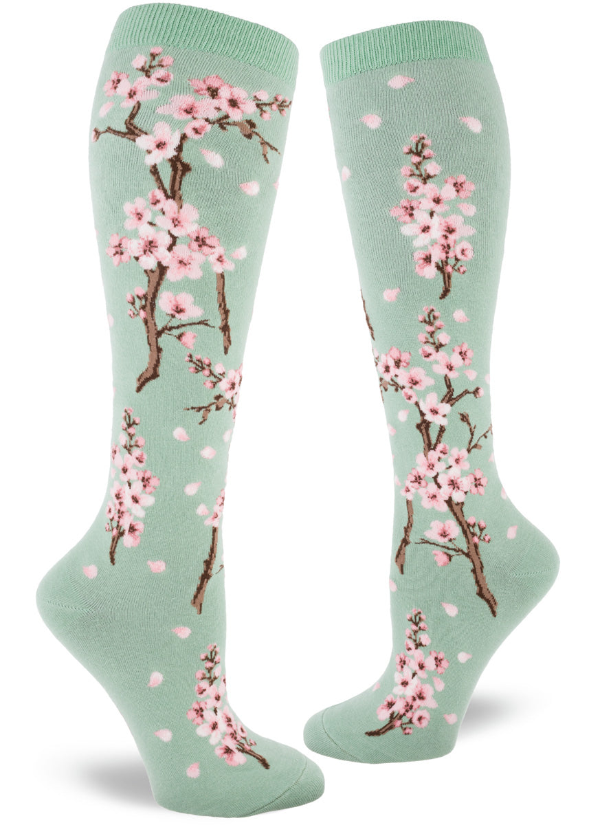 Pale green knee socks with branches of pink cherry blossoms and falling pink petals.
