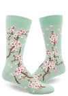 Light green crew socks for men with cherry blossom design of lowers and falling pink petals.