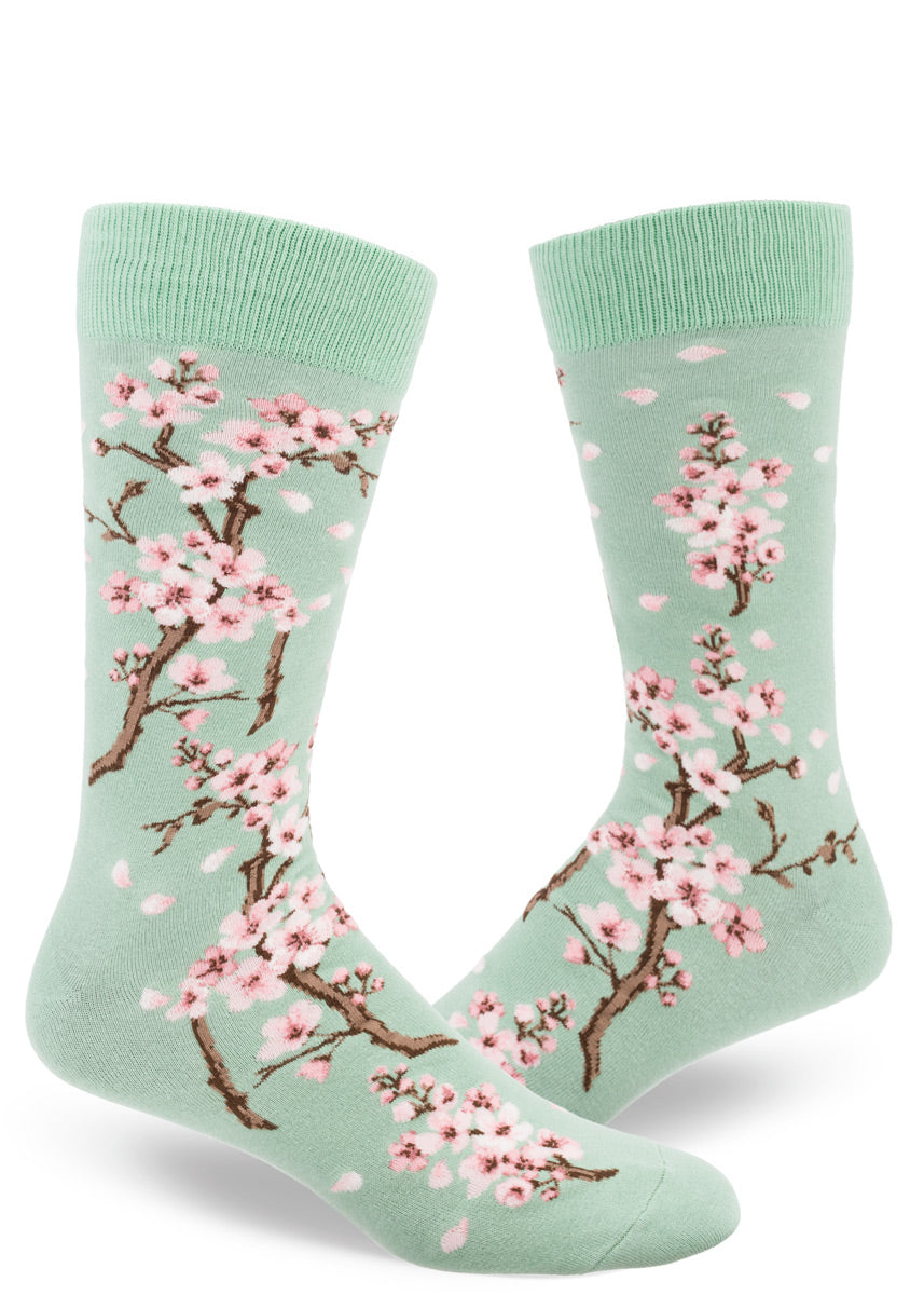 Light green crew socks for men with cherry blossom design of lowers and falling pink petals.