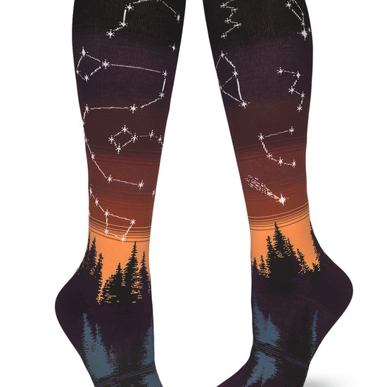 Knee-high socks with sunset glow gradient of purple and orange and star constellations over a forest and lake.