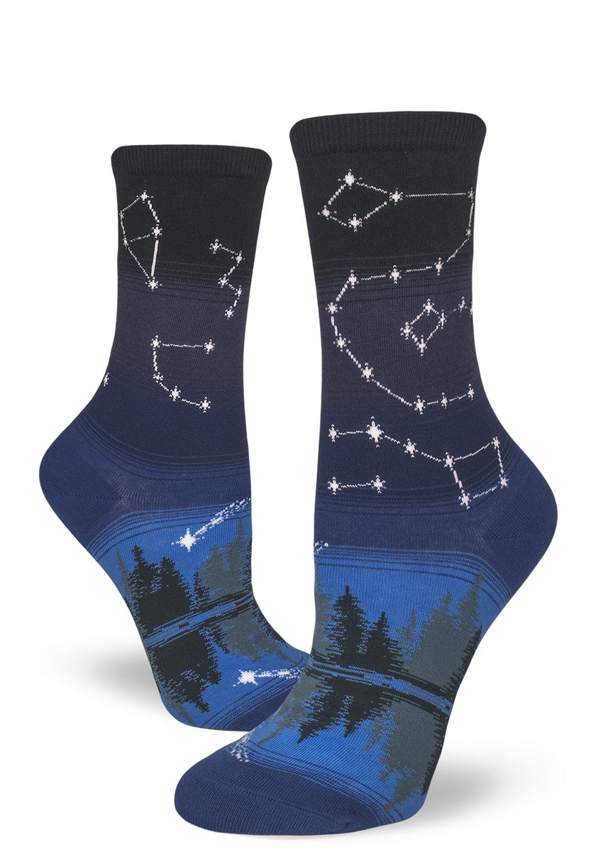 Blue crew socks for women with star constellations and shooting stars above a night forest and reflective lake.