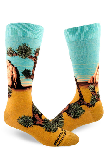 Men's crew socks with the words "Joshua Tree National Park" on the foot and scenery with Joshua trees, rock formations, blue sky and yellow sand.