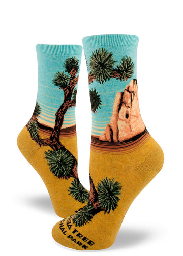 Crew socks for women with "Joshua Tree National Park" at the toe and Joshua trees, rock formation and scenic view of blue sky and yellow sand.