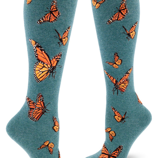 Dark teal knee socks with orange monarch butterflies in flight.