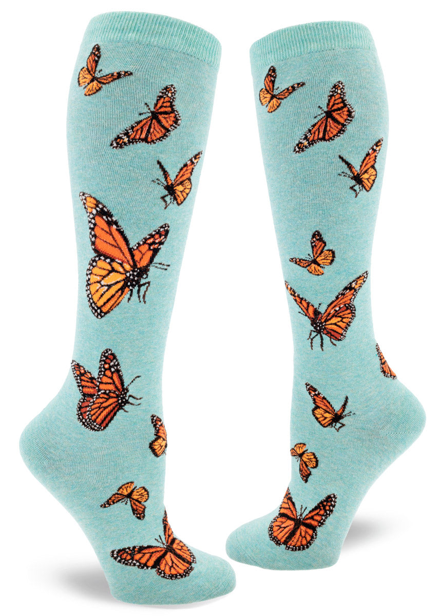 Light blue knee-high socks with orange monarch butterflies in flight in an allover pattern.