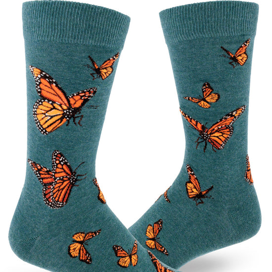 Teal crew socks for men with orange monarch butterflies flying in an allover pattern.