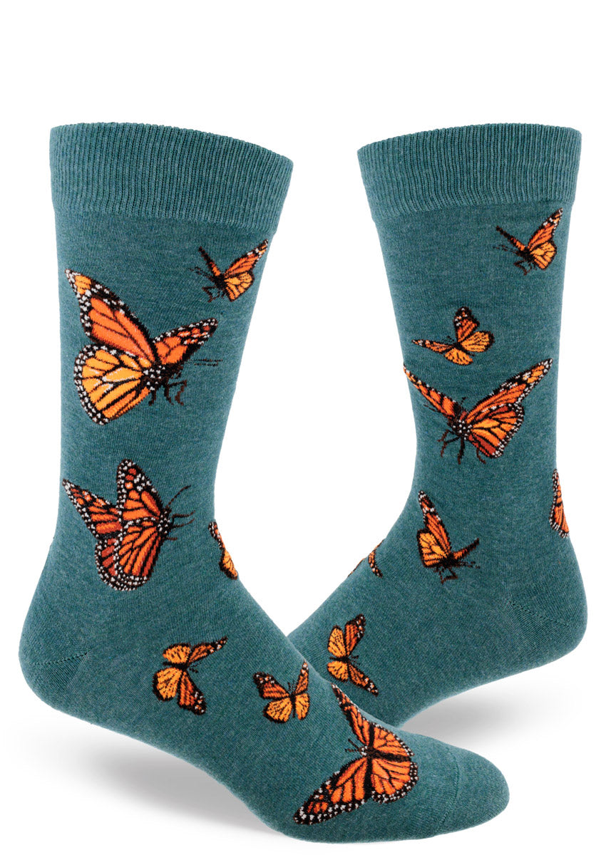 Teal crew socks for men with orange monarch butterflies flying in an allover pattern.