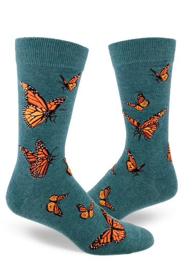 Teal crew socks for men with orange monarch butterflies flying in an allover pattern.