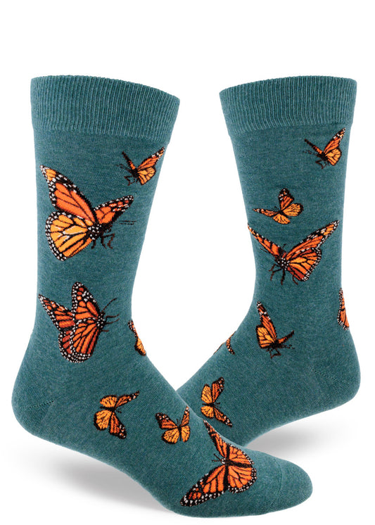 Teal crew socks for men with orange monarch butterflies flying in an allover pattern.