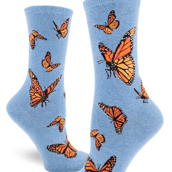 Light blue crew socks for women with orange monarch butterflies flying and flapping in different directions.