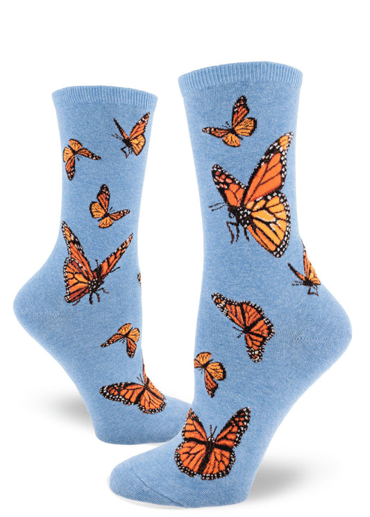 Light blue crew socks for women with orange monarch butterflies flying and flapping in different directions.
