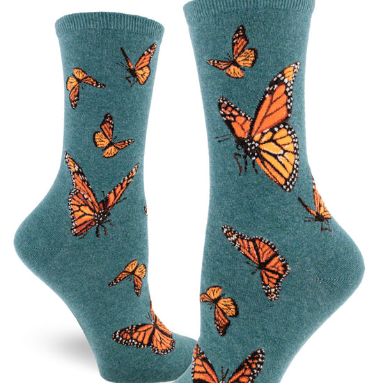 Teal crew socks for women with orange monarch butterflies flying in different directions in allover pattern.