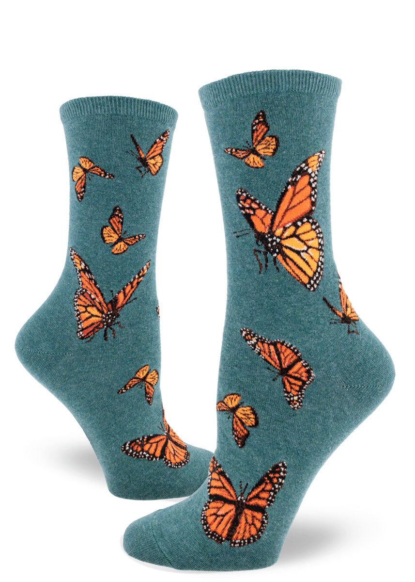 Teal crew socks for women with orange monarch butterflies flying in different directions in allover pattern.