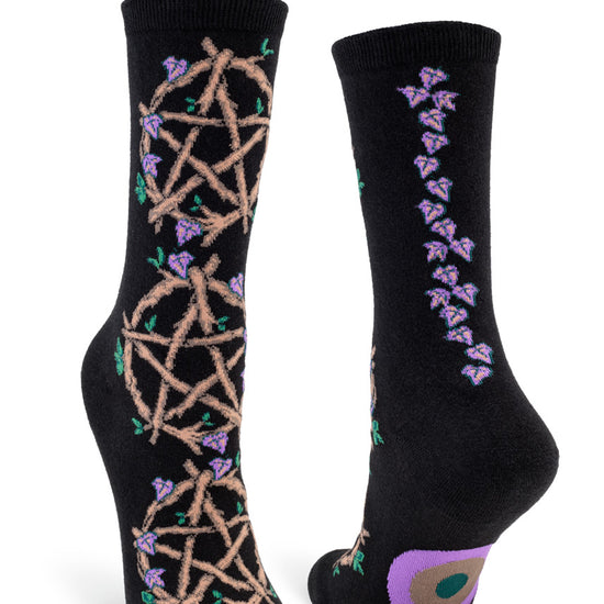 Black crew socks for women with intricate pentacles formed from brown twigs with vines of purple leaves rising up the back seam.