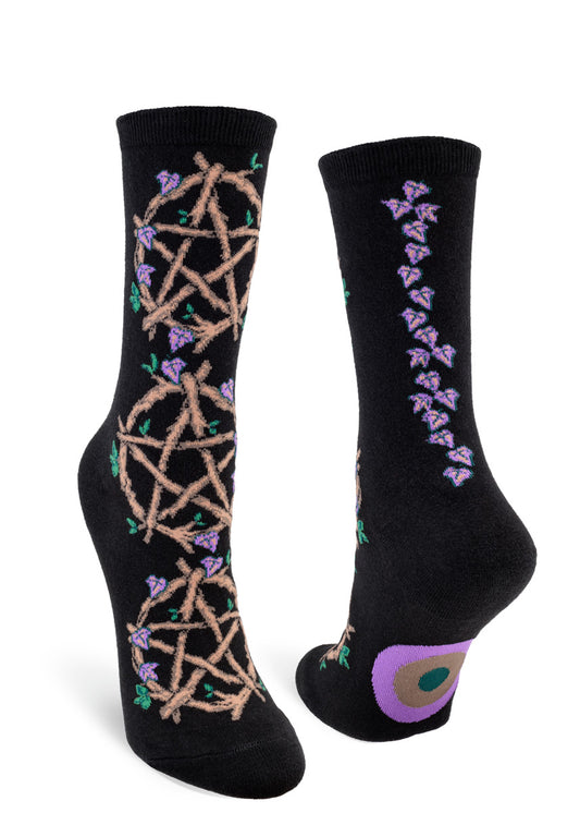 Black crew socks for women with intricate pentacles formed from brown twigs with vines of purple leaves rising up the back seam.