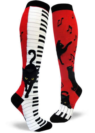 Red, black and white knee socks with black cats walking down piano keys and pawing at music notes.