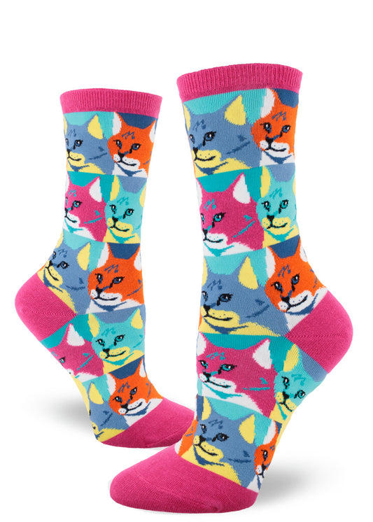 Colorful women's crew socks with allover repeating pattern of cat faces in pop art style in pink, orange, blue and yellow.