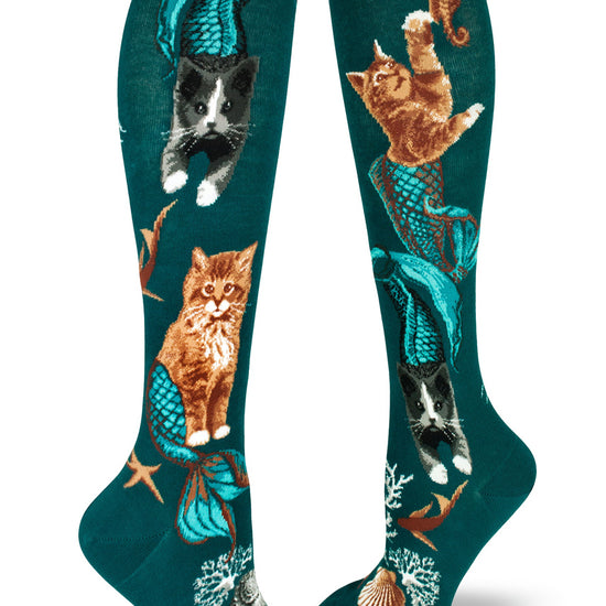 Teal knee socks with mermaid cat design of orange and black and white cats with blue tails chasing fish.