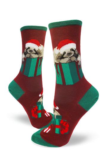 Red crew socks for women with sloths in Santa hats lying on top of green Christmas presents.