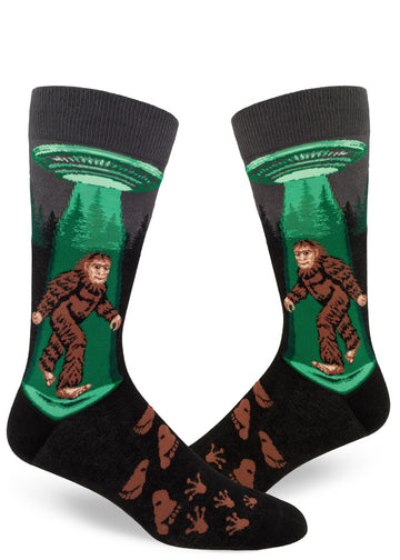 Charcoal men's crew socks with Sasquatch walking under a flying saucer with a green glowing beam, alien and humanoid footprints.