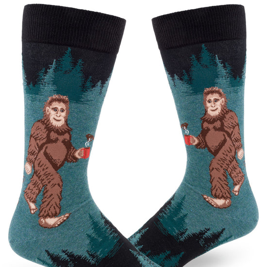 Dark teal men's crew socks with Sasquatch holding a mug of coffee with forest tree pattern above and below.