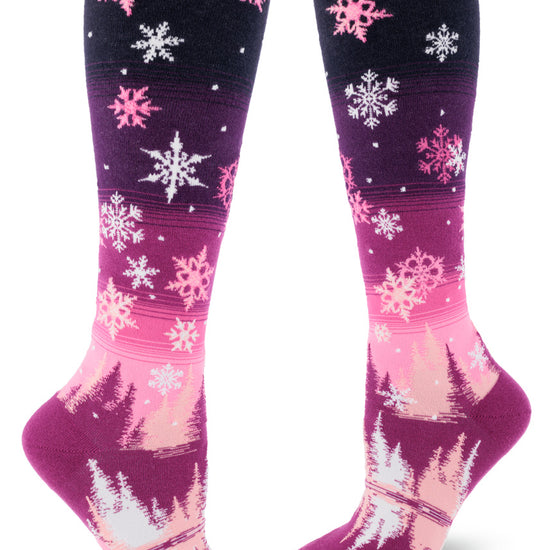 Pink gradient knee socks with pink and white snowflakes above falling on trees below.