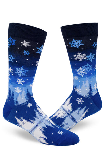 Blue gradient men's crew socks with allover snowflake design that shows snow falling through a night sky over trees above a reflective pond.