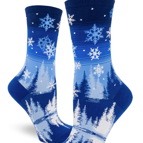 Blue and white crew socks for women with  snowflakes falling over a pond surrounded by snowy trees on a winter night.