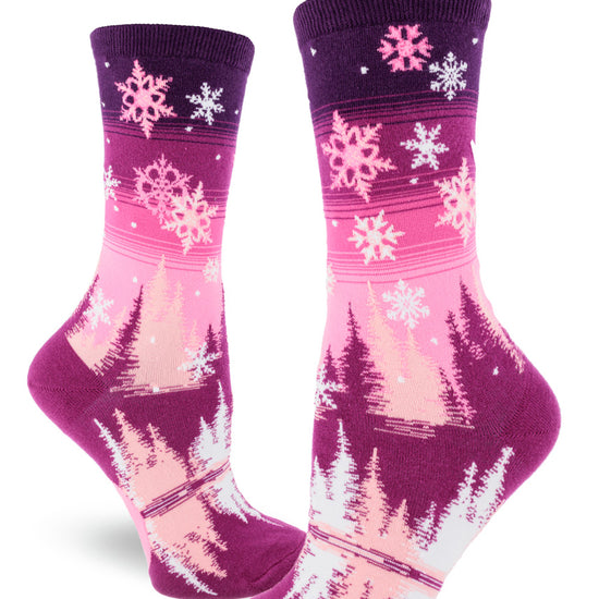 Purple and pink gradient women's crew socks with snowflakes falling above pink, white and magenta trees surrounding a reflective pond.