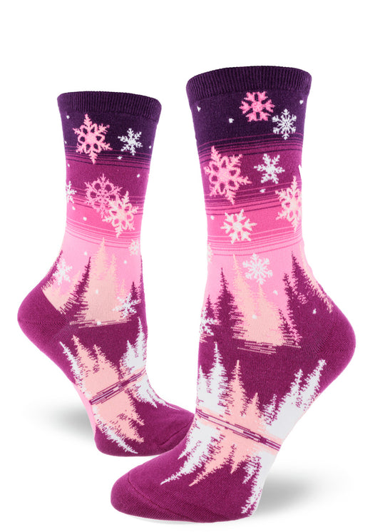 Purple and pink gradient women's crew socks with snowflakes falling above pink, white and magenta trees surrounding a reflective pond.