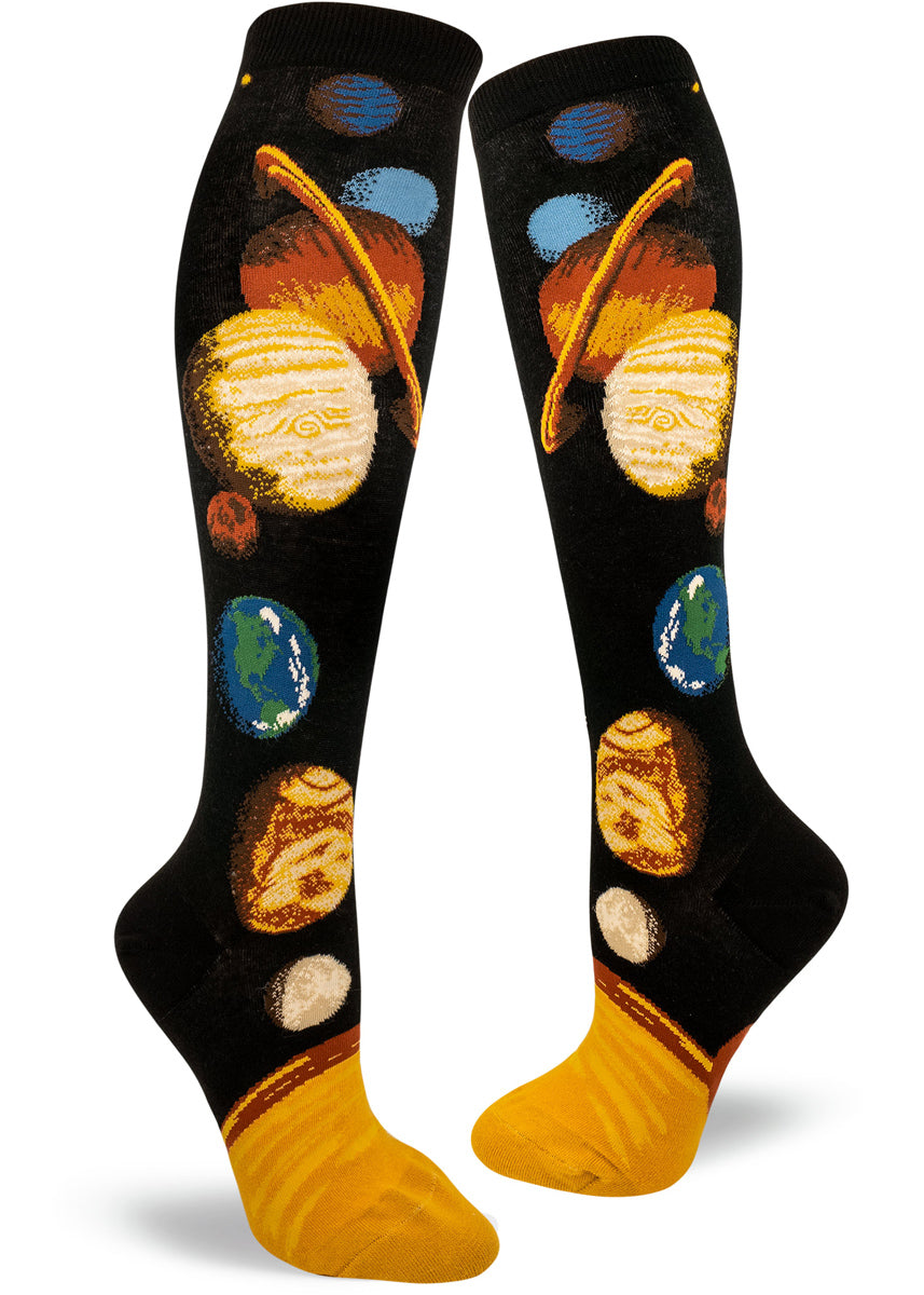 Black background knee socks with a colorful solar system design that includes all the planets aligned leading upward from the sun at the base.