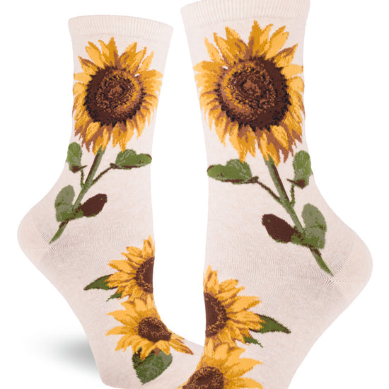 Cream colored crew socks for women with a sunflower design that shows large realistic flowers with yellow petals and brown centers, and green leaves and stems.