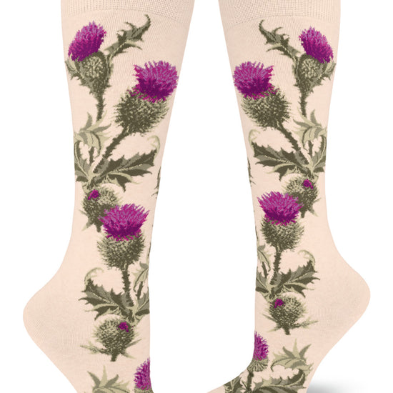 Cream colored knee socks show a floral pattern with realistic purple thistles  and spiky green leaves and stems that grow up along the sides of the socks.