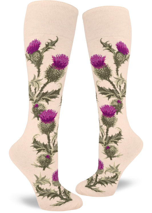 Cream colored knee socks show a floral pattern with realistic purple thistles  and spiky green leaves and stems that grow up along the sides of the socks.