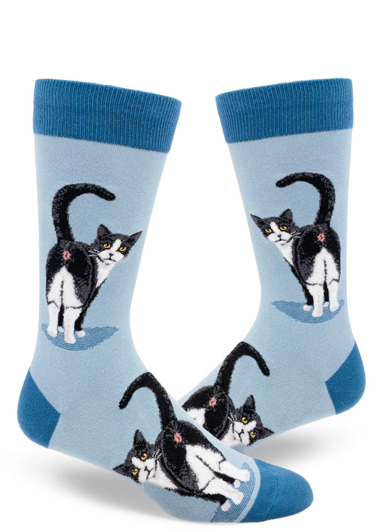 Light blue men's novelty crew socks with black and white tuxedo cats showing their butts with their tails raised and faces turned backward.