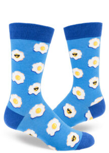 Playful blue men's crew socks sport an allover sunny-side-up egg motif, some with smirking faces and cool sunglasses.