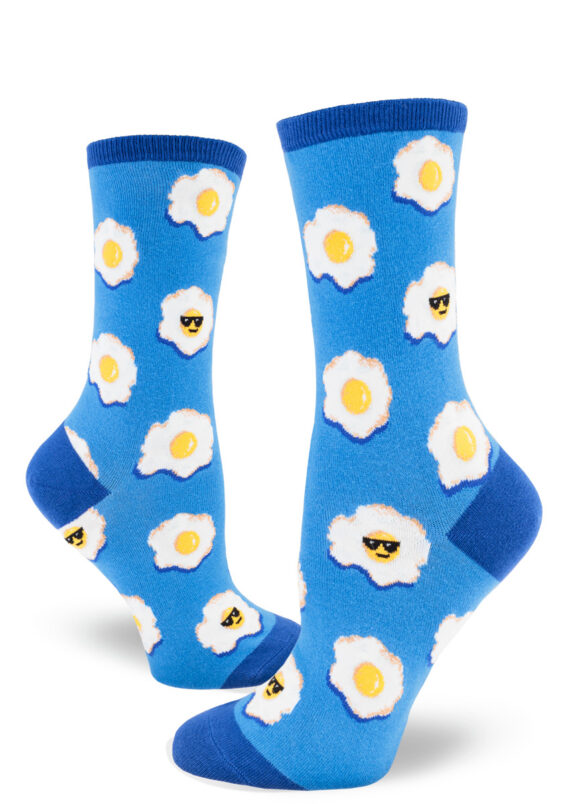 Playful blue women's crew socks sport an allover sunny-side-up egg motif, some with smirking faces and cool sunglasses.