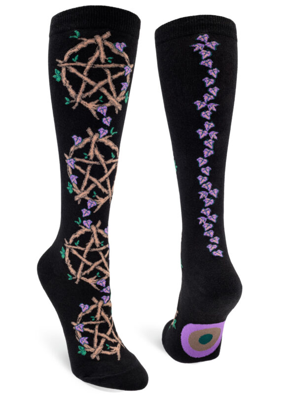 Knee-high socks with a black background featuring a pattern of pentacles made from twigs with purple vines and green leaves interspersed, plus a purple vine up the backseam.